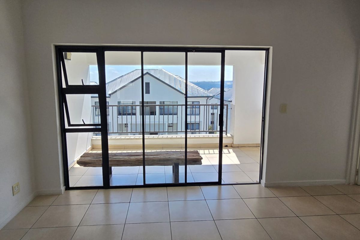 Bright and spacious living area featuring neutral tiled flooring and large sliding glass doors that open onto a private balcony.