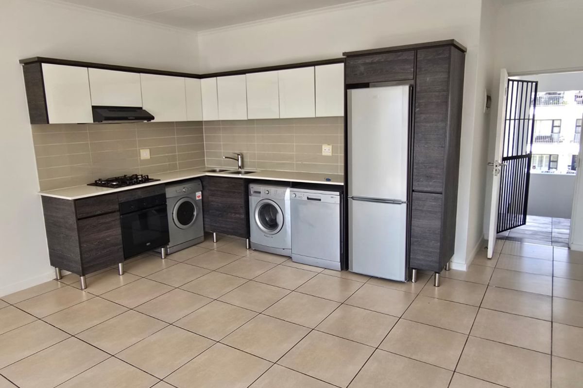 Modern kitchen featuring two-tone cabinetry, gas hob, under-counter oven, and tiled flooring, with an adjacent security gate leading to the exterior.