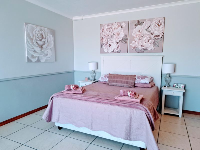 A well-maintained bedroom featuring neutral wall tones, a decorative chair rail, and tiled flooring throughout.