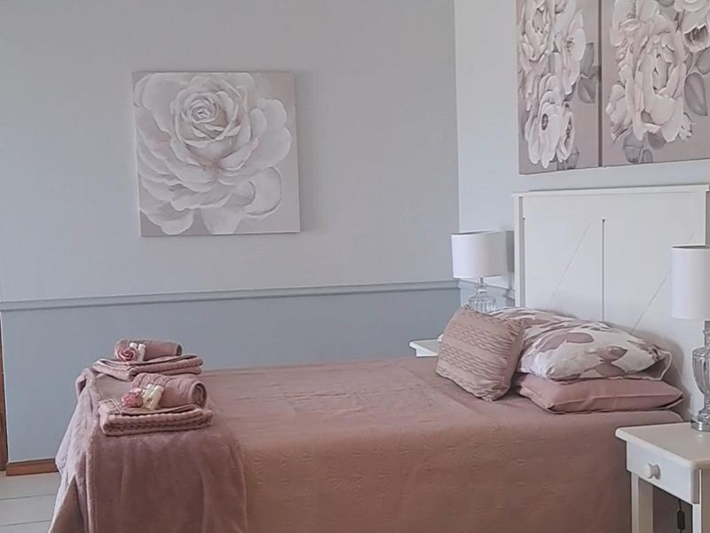 A well-maintained bedroom featuring neutral tiled flooring, coved ceilings with recessed lighting, and a decorative dado rail finish.