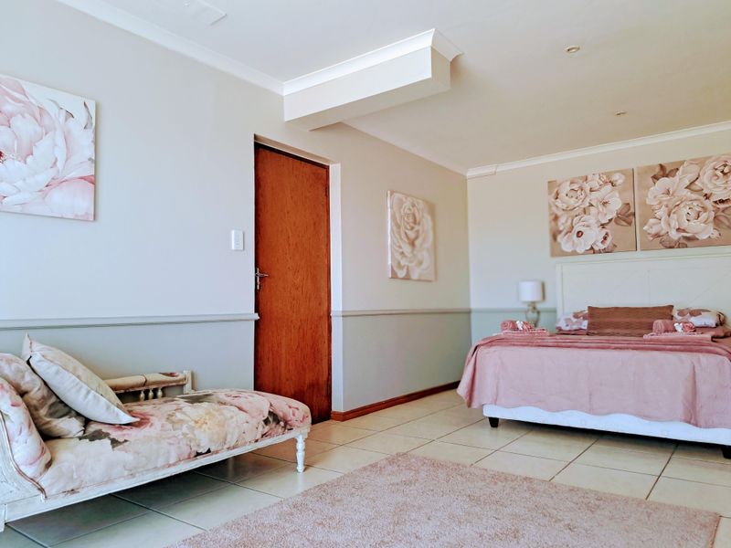 Spacious bedroom featuring neutral walls with dado rail, tiled flooring, recessed downlighting, and coved cornicing.