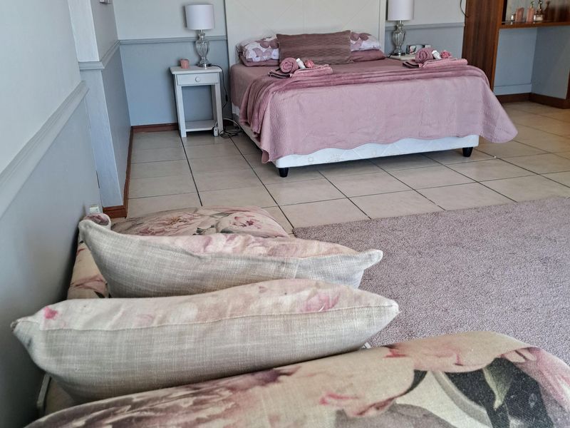 Spacious bedroom featuring tiled flooring, a built-in wardrobe, and decorative chair rail molding.