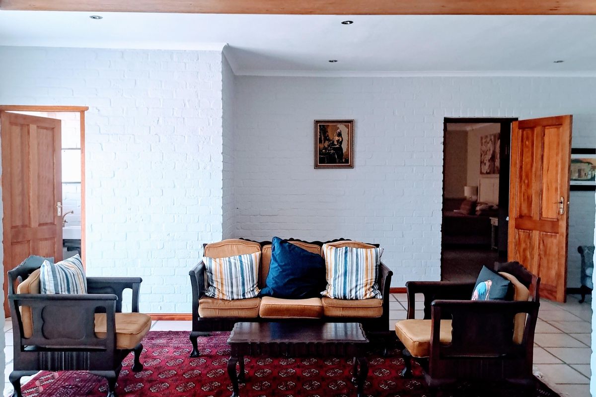 Spacious living area featuring white painted exposed brick walls, tiled flooring, and timber door frames, creating a bright and open atmosphere.