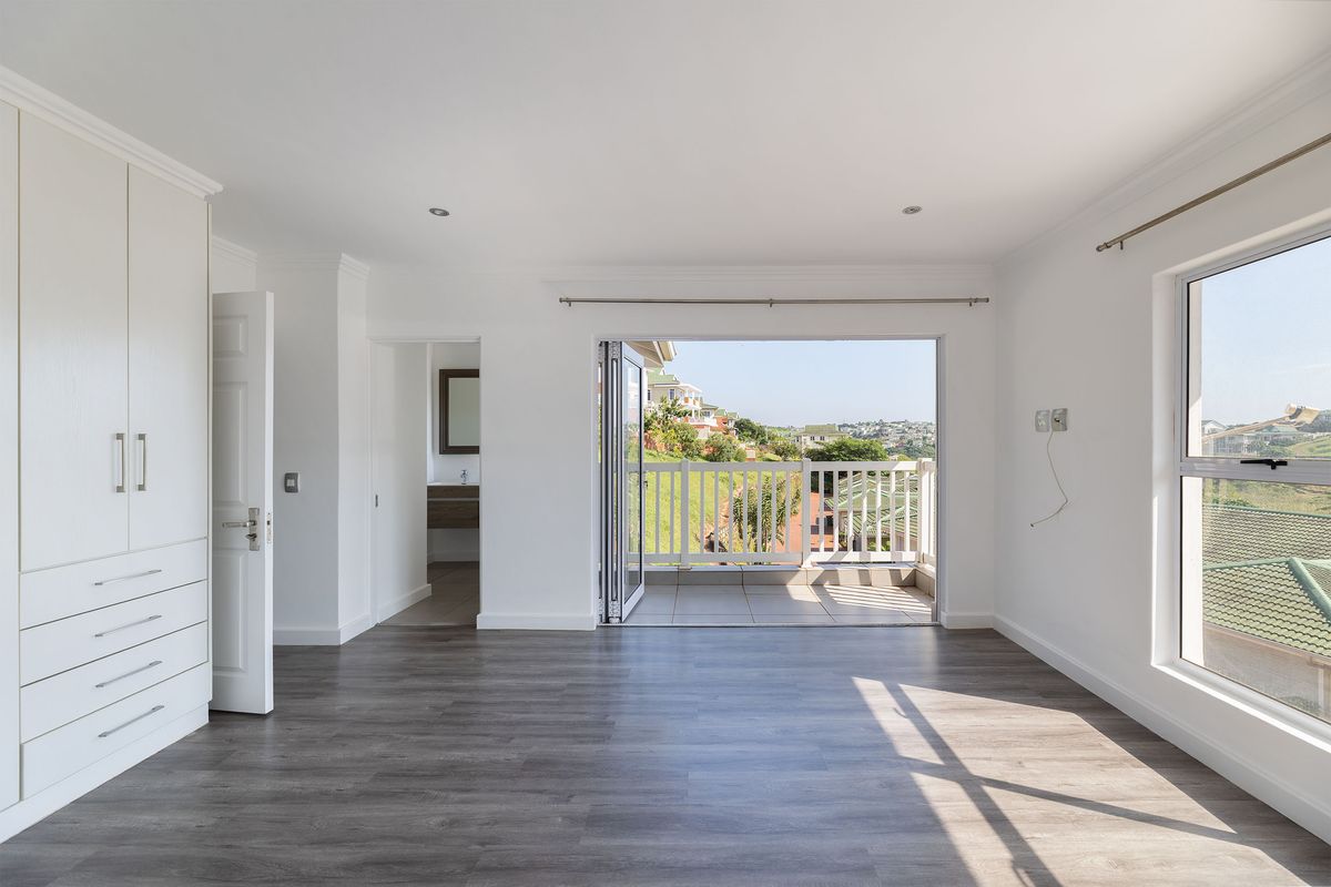 Spacious bedroom featuring modern laminate flooring, built-in cupboards, and direct access to a private balcony with scenic views.