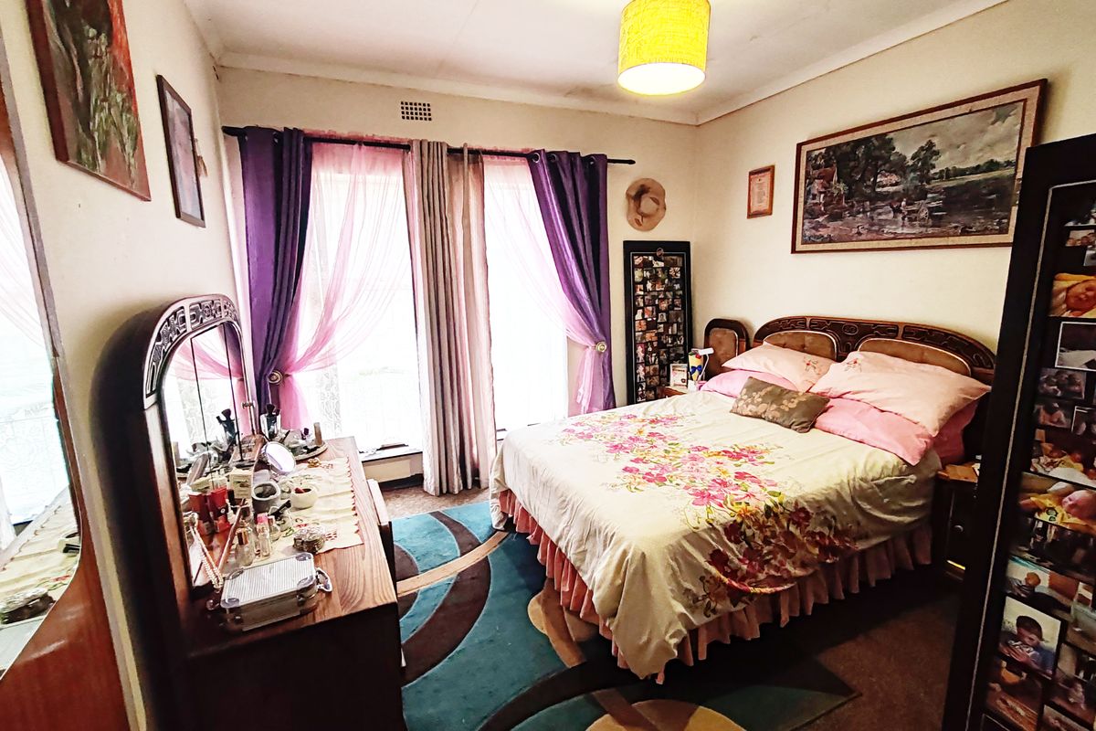 A bedroom featuring a central light fixture and a ventilation grille, with visible signs of wear on the ceiling plaster.