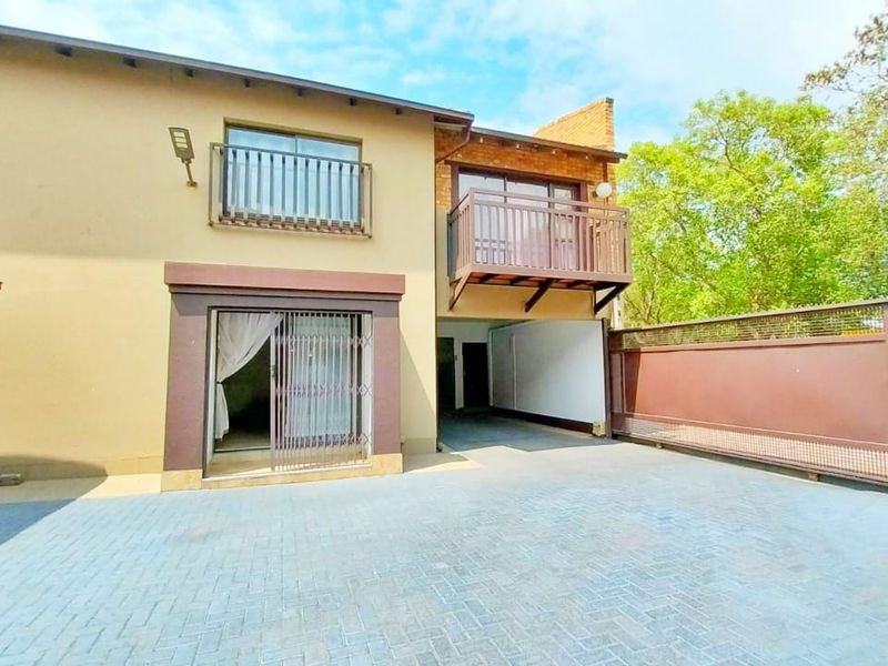 Front exterior view of the property featuring a paved driveway, sliding gate, and upper-level balcony access.