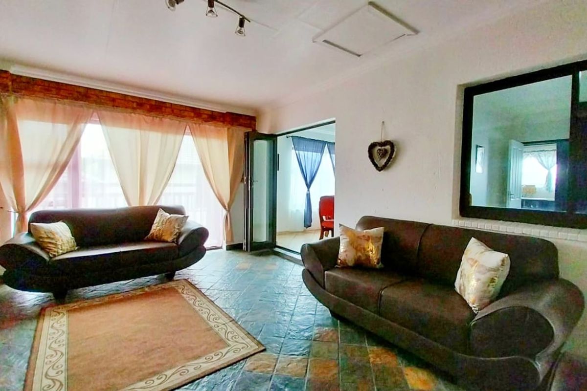 Spacious living room featuring tiled flooring, exposed brick accents, and large sliding glass doors providing natural light and access to the adjoining space.