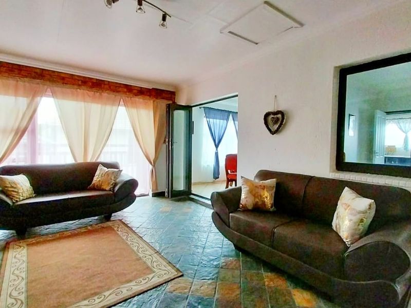 Spacious living room featuring tiled flooring, exposed brick accents, and large sliding glass doors providing natural light and access to the adjoining space.