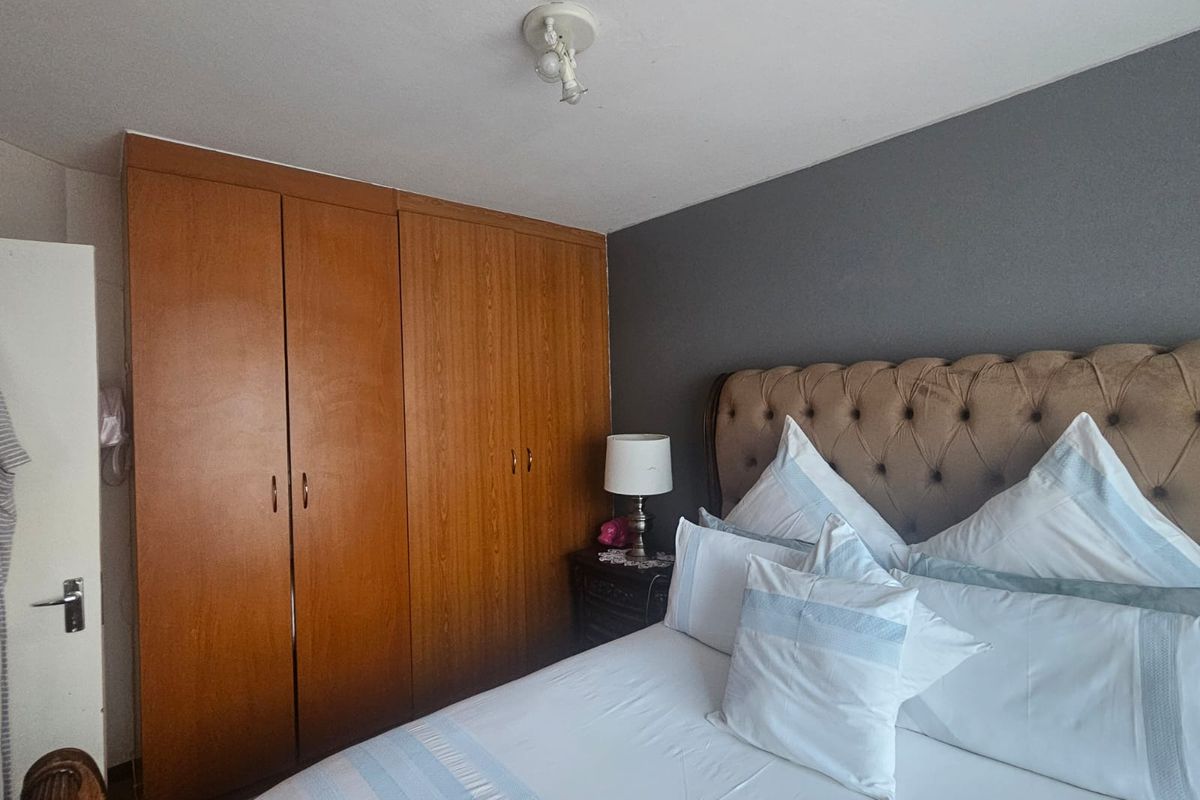 A bedroom featuring built-in wooden wardrobes and a dark accent wall, providing functional storage and a neutral foundation for interior design updates.