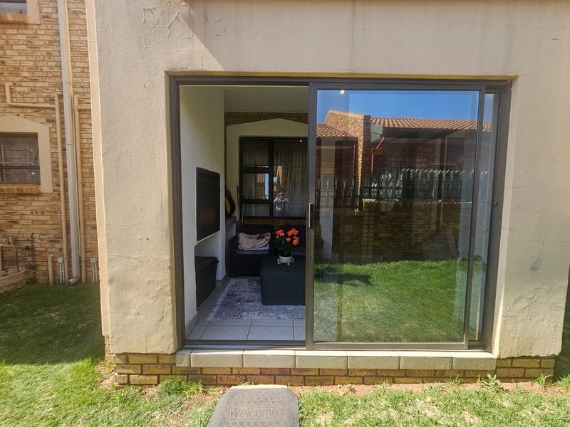 A covered patio area featuring a built-in braai, tiled flooring, and a large sliding glass door providing access to the garden.