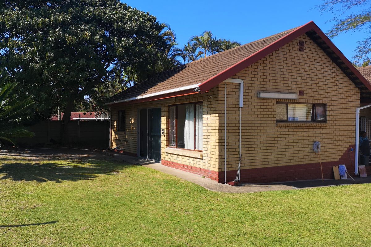 Rear view of a face brick house featuring a tiled roof, aluminium window frames, and a sliding door leading to the garden.