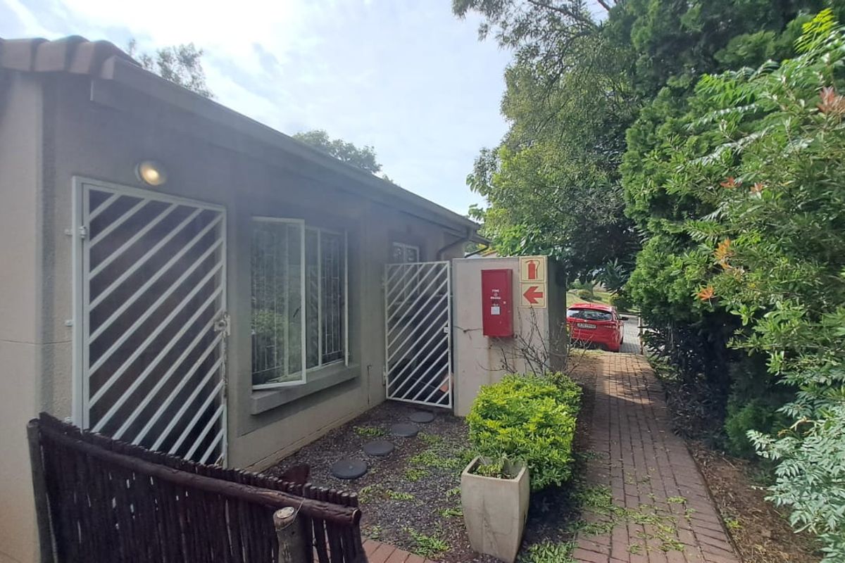 Exterior view of the townhouse rear area featuring a paved walkway, security gates, and a wall-mounted fire hose reel.