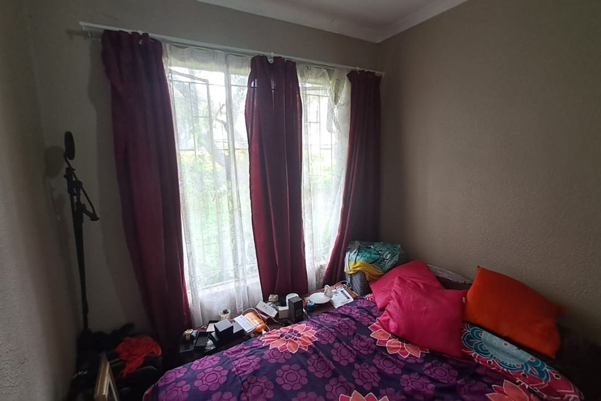 A standard bedroom featuring a window with security bars and coving detail, providing a functional space for rest.