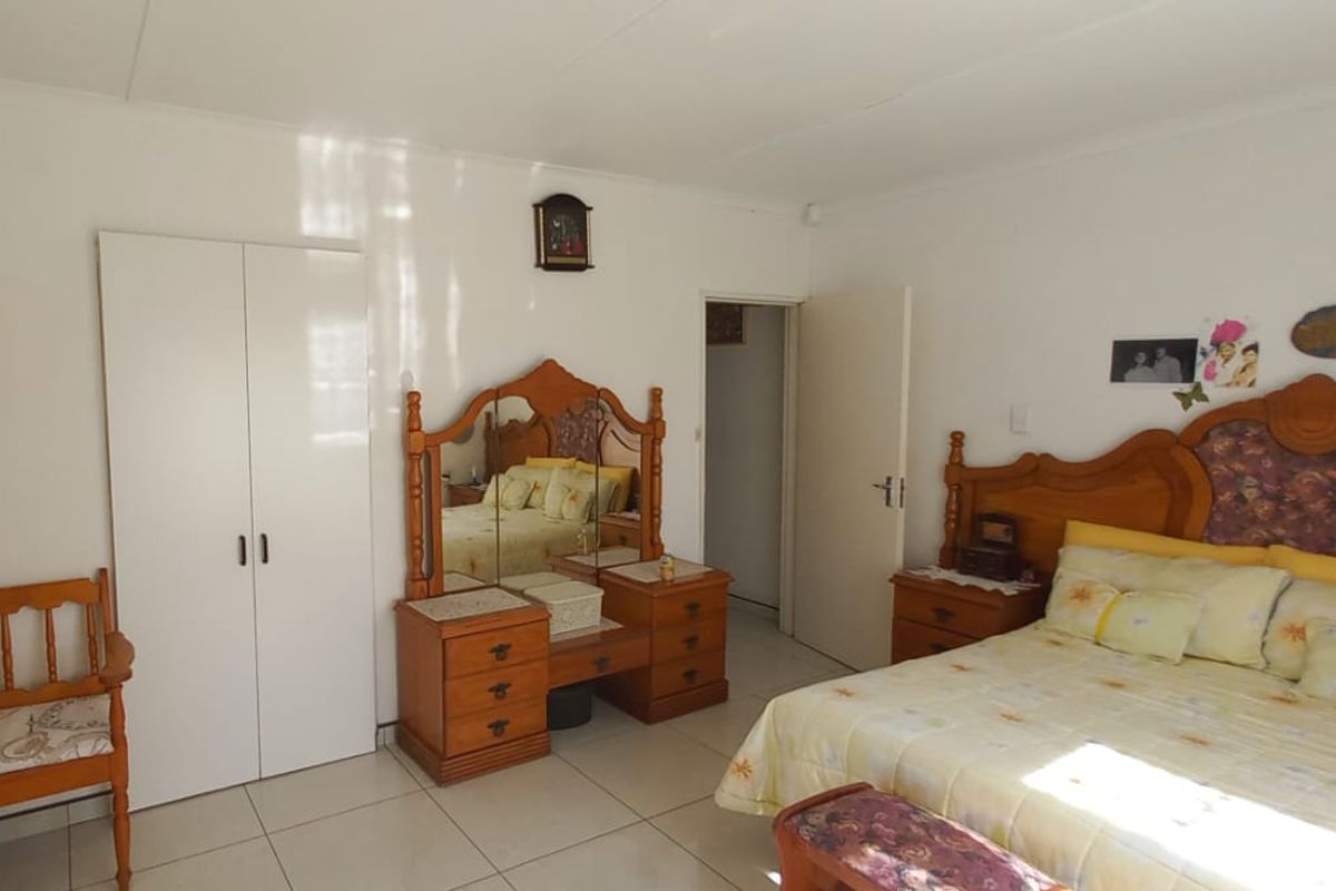 A spacious bedroom featuring neutral tiled flooring and built-in cupboards, offering a clean and functional layout.