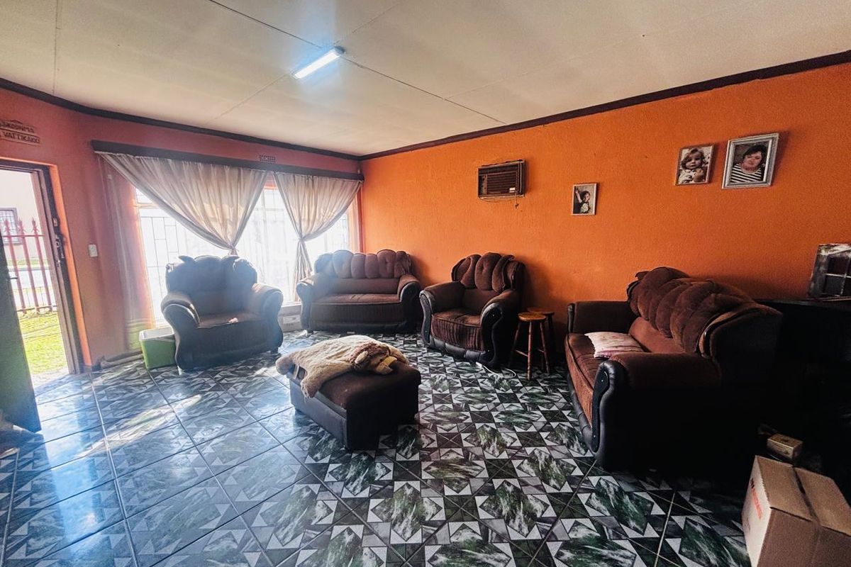 A living room featuring patterned floor tiles, orange walls, and a built-in wall-mounted air conditioning unit.