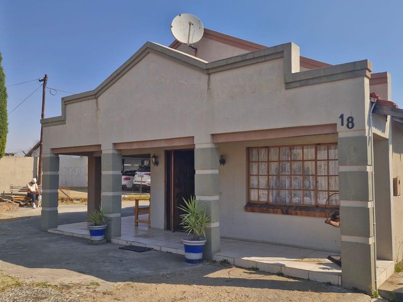 Front elevation of a single-story house featuring a covered entrance porch, tiled flooring, and a satellite dish mounted on the roof.