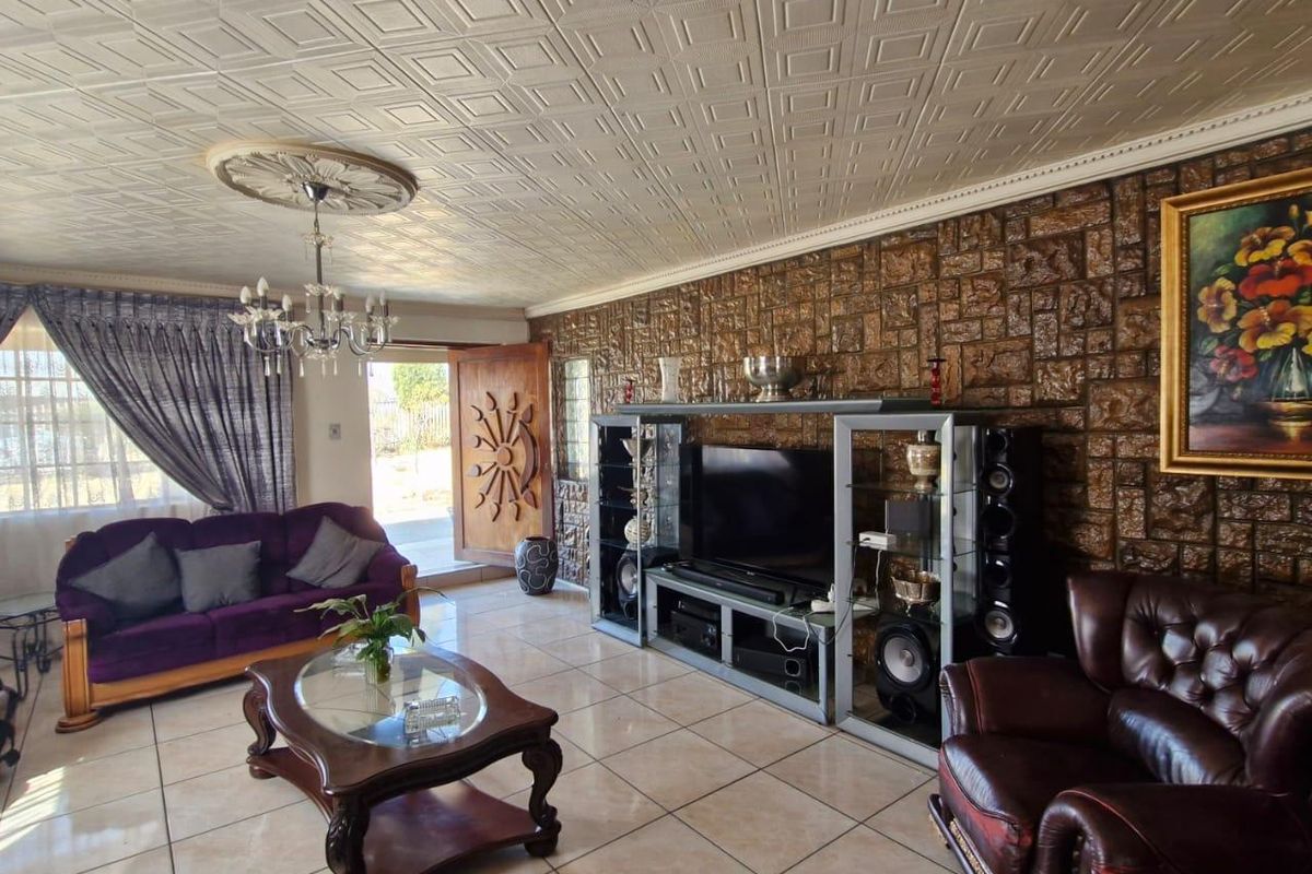 Spacious living room featuring a textured ceiling, stone-cladding feature wall, and large ceramic floor tiles, providing a distinct retro aesthetic.