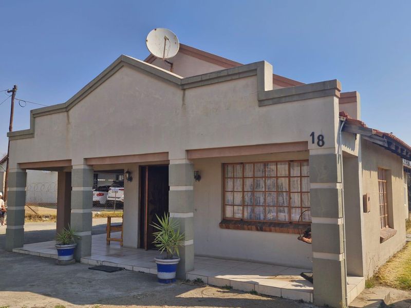 Front elevation of a single-story house featuring a covered entrance porch, tiled flooring, and a satellite dish mounted on the roof.