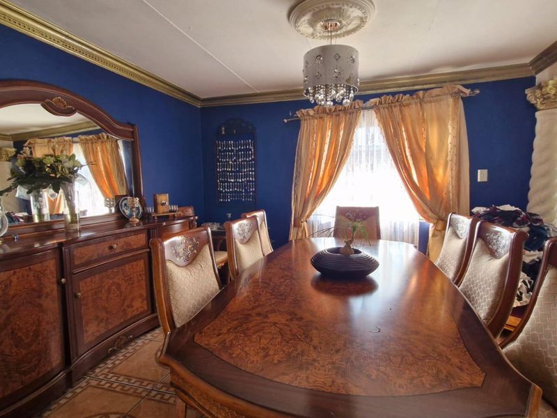A formal dining room featuring decorative ceiling molding, a central chandelier, and tiled flooring, providing a classic space for entertaining.