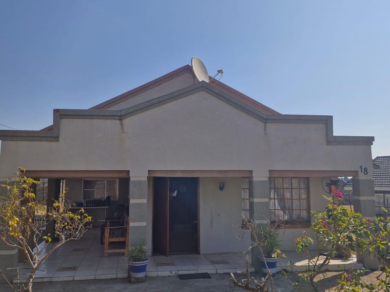 Front elevation of a single-story residential house featuring a covered patio entrance, tiled flooring, and a satellite dish mounted on the roof.