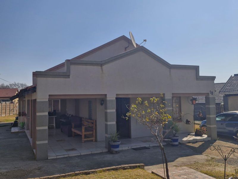 A single-story residential home featuring a covered front porch, tiled entrance area, and a paved driveway with a small front garden.