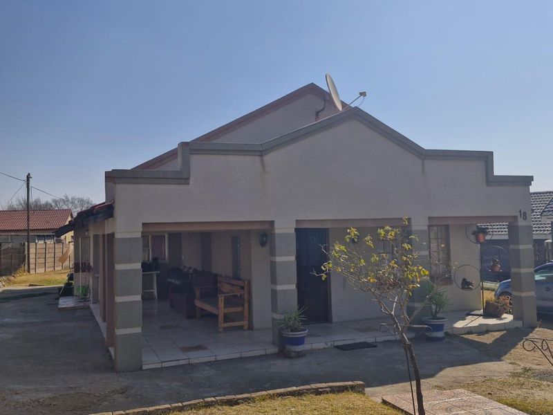 Front elevation of a single-story house featuring a covered patio entrance, tiled flooring, and a paved driveway area.
