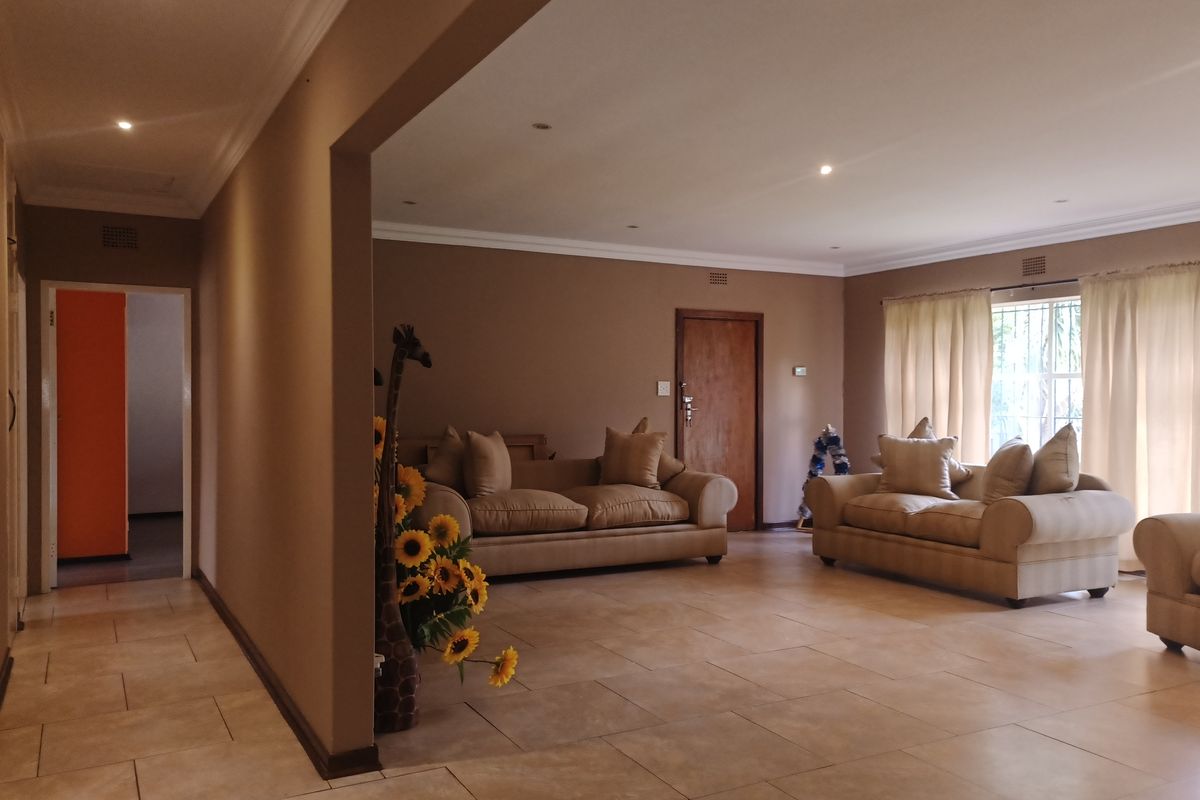 Spacious open-plan living area featuring neutral wall tones, tiled flooring, and recessed lighting, providing a versatile space for relaxation and entertaining.