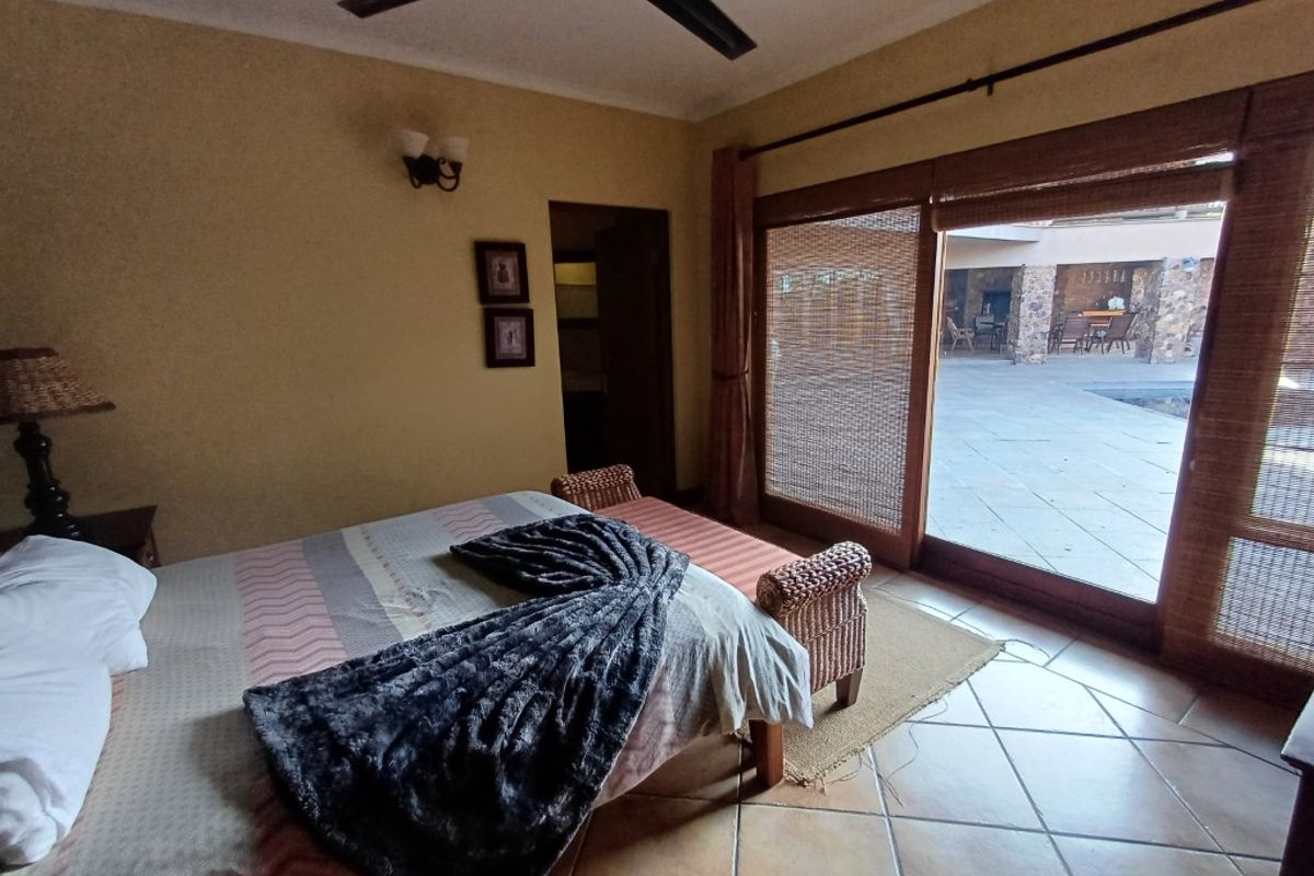 Spacious bedroom featuring tiled flooring, a ceiling fan, and large sliding glass doors providing direct access to an outdoor patio area.