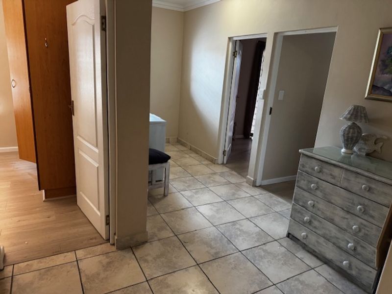 A tiled hallway area connecting multiple rooms, featuring neutral wall tones and built-in storage cabinetry.