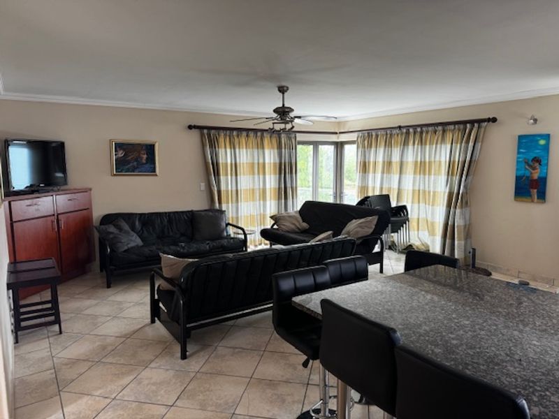 Spacious open-plan living and dining area featuring tiled flooring, a ceiling fan, and large sliding doors providing access to the exterior.