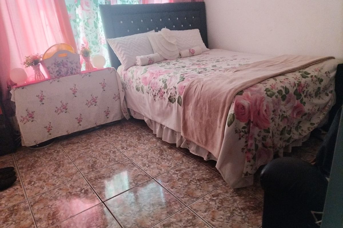 A bedroom featuring tiled flooring and a window with curtains.