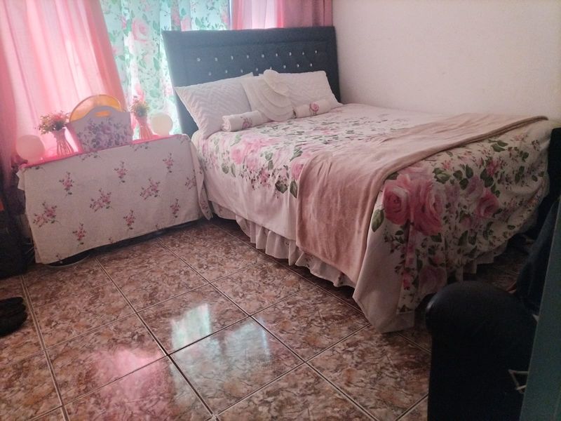 A bedroom featuring tiled flooring and a window with curtains.