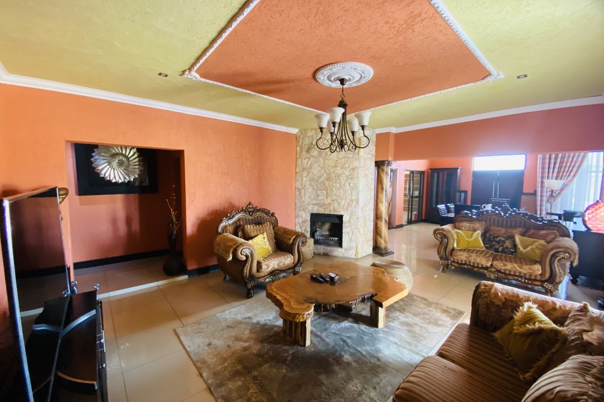 Spacious living room featuring a stone-clad fireplace, decorative ceiling molding with a central rose, and tiled flooring.