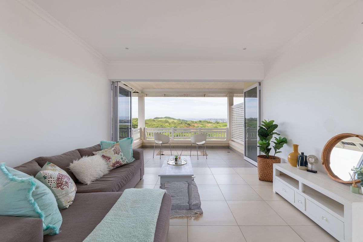 Bright living room featuring large bi-fold doors that open onto a covered balcony with scenic landscape views.