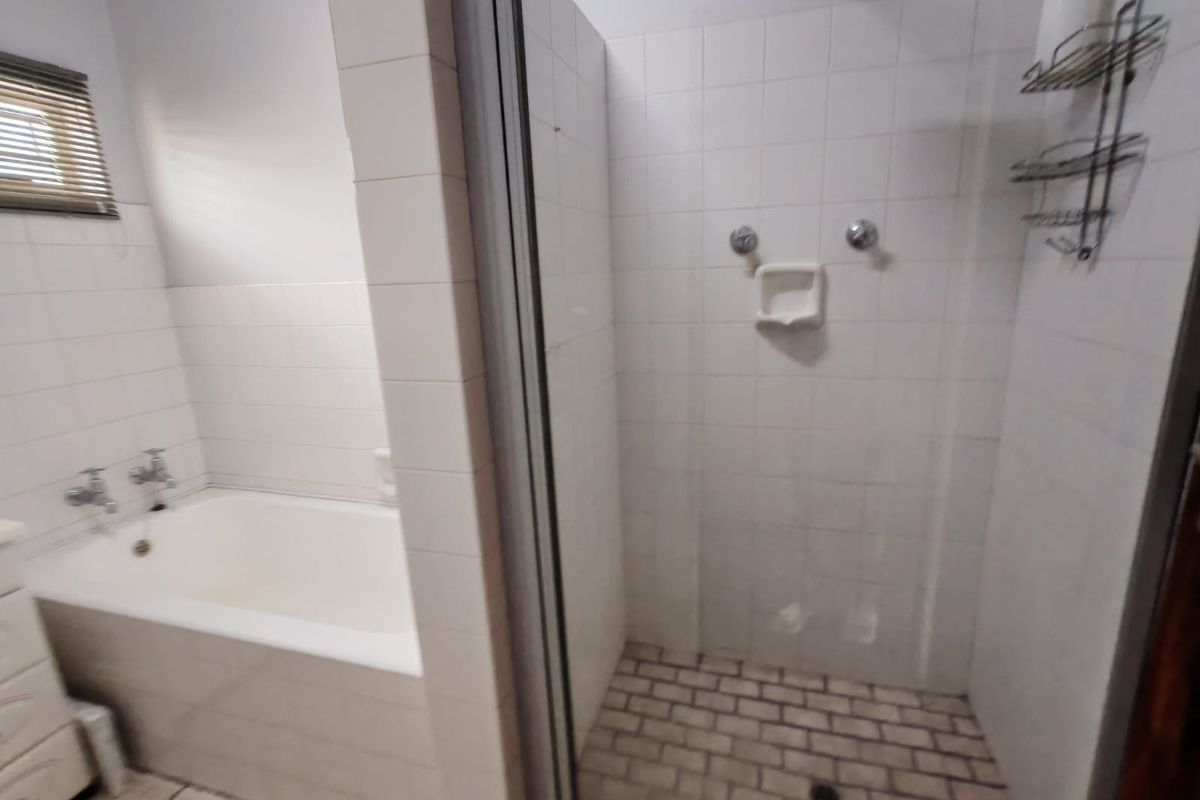 A functional bathroom featuring a built-in bathtub and a separate walk-in shower with tiled finishes.