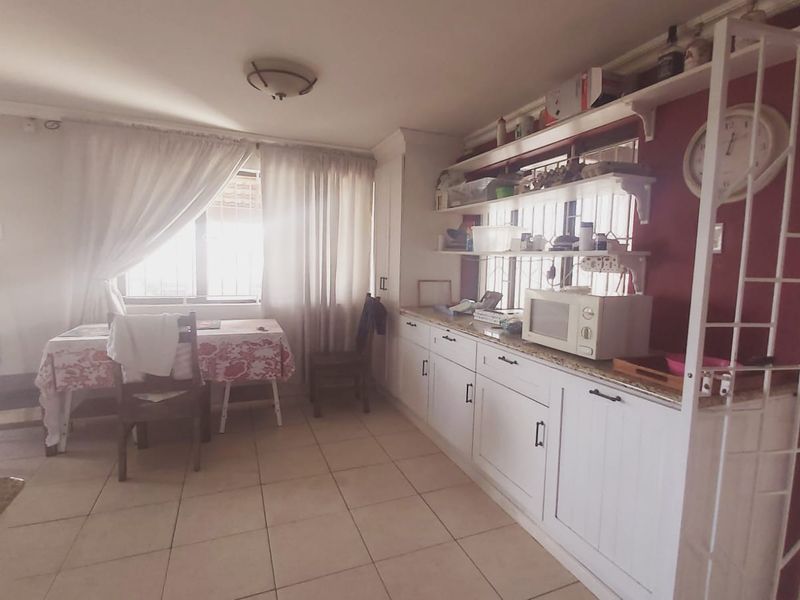 A functional kitchen area featuring white built-in cabinetry, open shelving, and tiled flooring, offering potential for a modern renovation.