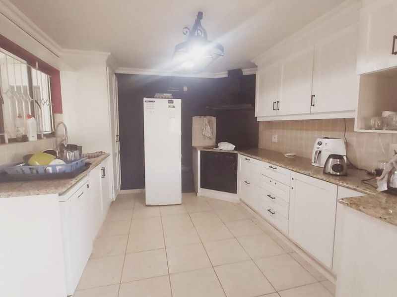 A functional kitchen featuring white cabinetry, granite countertops, tiled flooring, and built-in appliances, offering a practical layout for daily meal preparation.