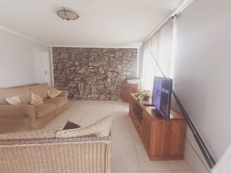 A living room featuring a prominent stone accent wall and tiled flooring, offering a neutral base for interior design updates.