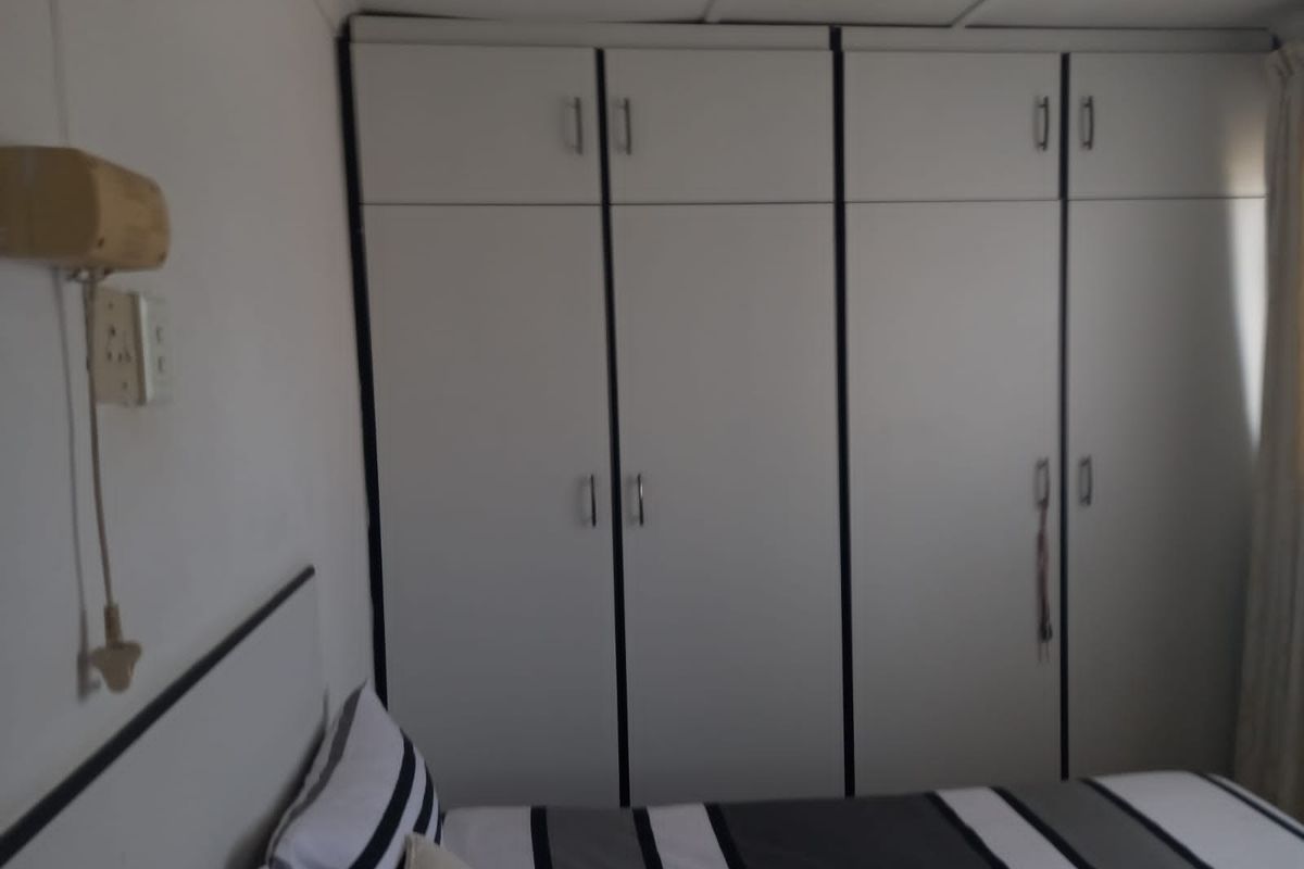 A bedroom featuring built-in floor-to-ceiling wardrobes with white cabinetry and dark trim, providing ample storage space.