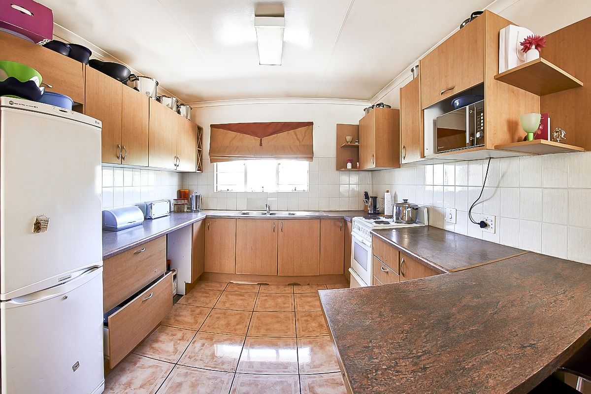 A functional U-shaped kitchen featuring laminate cabinetry, tiled flooring, and a tiled backsplash, offering ample counter space and integrated cooking appliances.