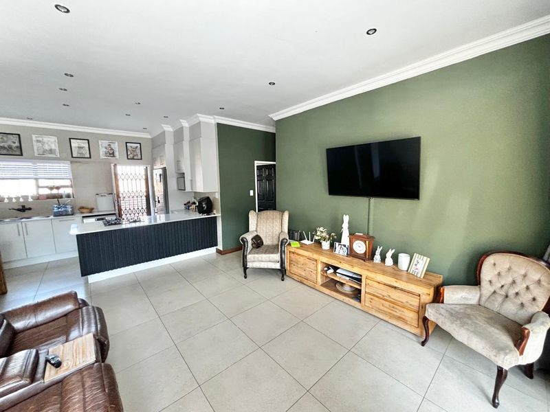 Spacious open-plan living area featuring a modern kitchen with island, stone countertops, gas hob, and neutral tiled flooring throughout.