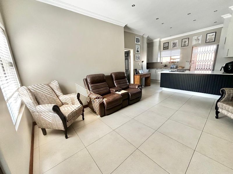 Spacious open-plan living area featuring large format floor tiles, recessed lighting, and a modern kitchen island with integrated hob and cabinetry.