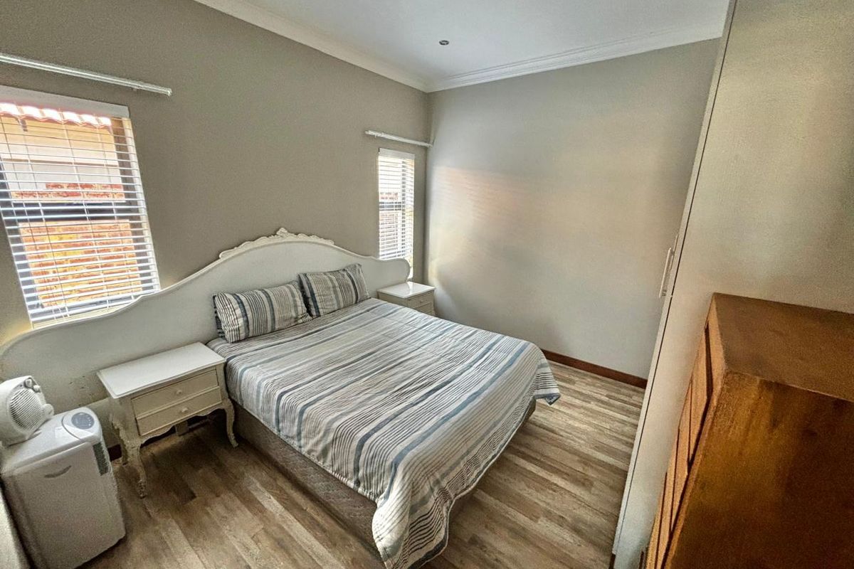 A well-maintained bedroom featuring laminate flooring, built-in cupboards, and recessed downlighting, offering a clean and functional living space.