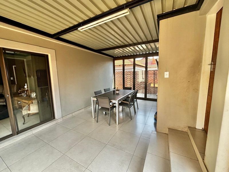 A covered patio area featuring tiled flooring, a corrugated metal roof, and sliding glass doors providing access to the interior living space.