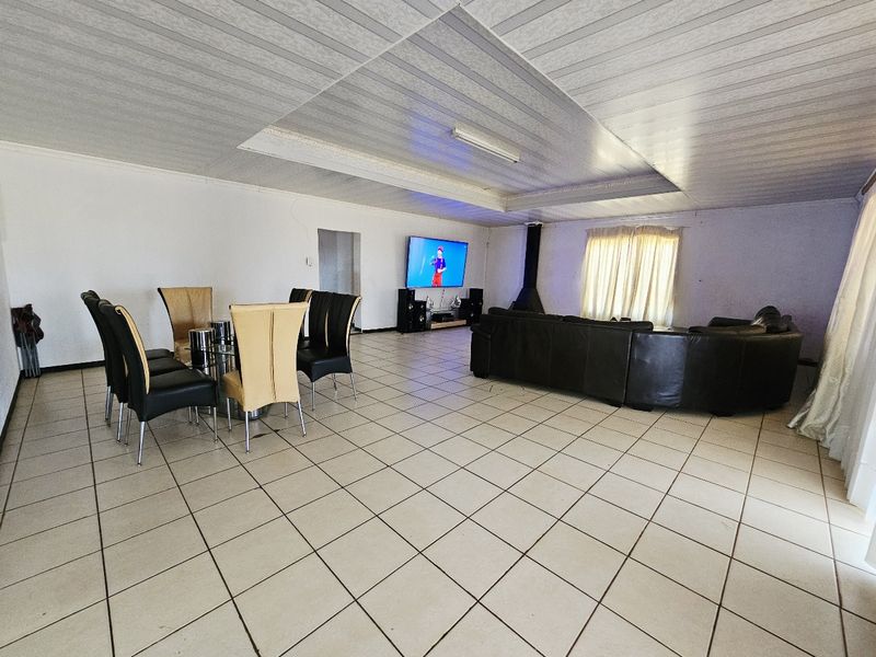 Spacious open-plan living and dining area featuring tiled flooring, a suspended ceiling, and a central freestanding fireplace.