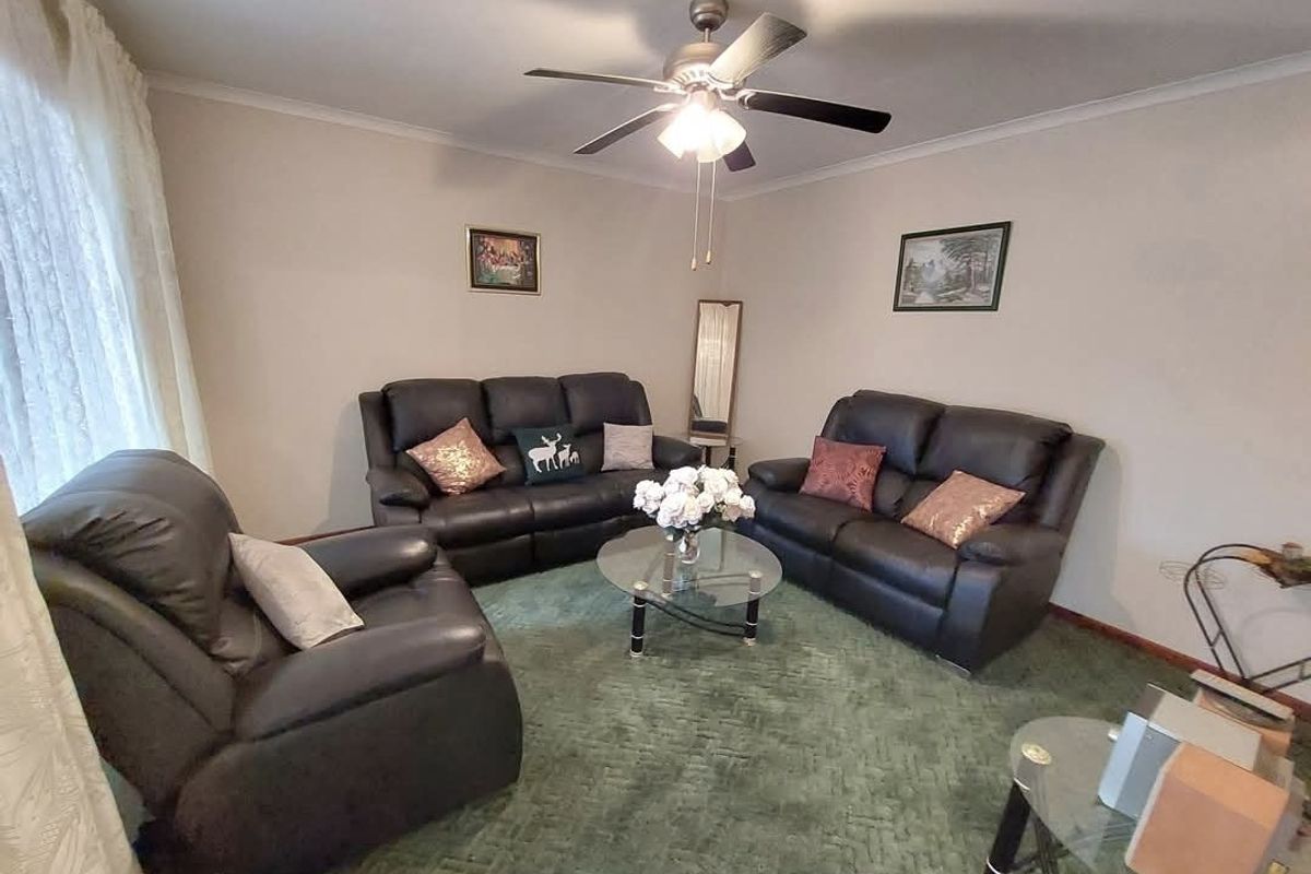 A living room featuring a ceiling fan and wall-to-wall carpeting, providing a functional space for relaxation.