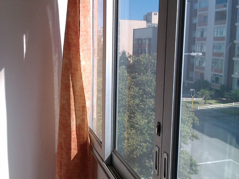A view from an apartment window looking out over a street and neighbouring residential buildings.