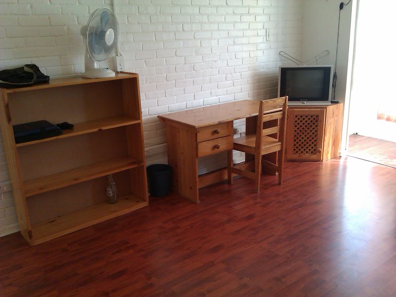 A living area featuring a painted white brick wall and laminate flooring, with access to an outdoor space.