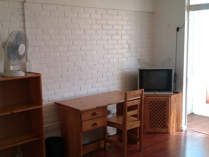 A living area featuring laminate flooring, a painted brick feature wall, and a glass door providing access to an outdoor space.