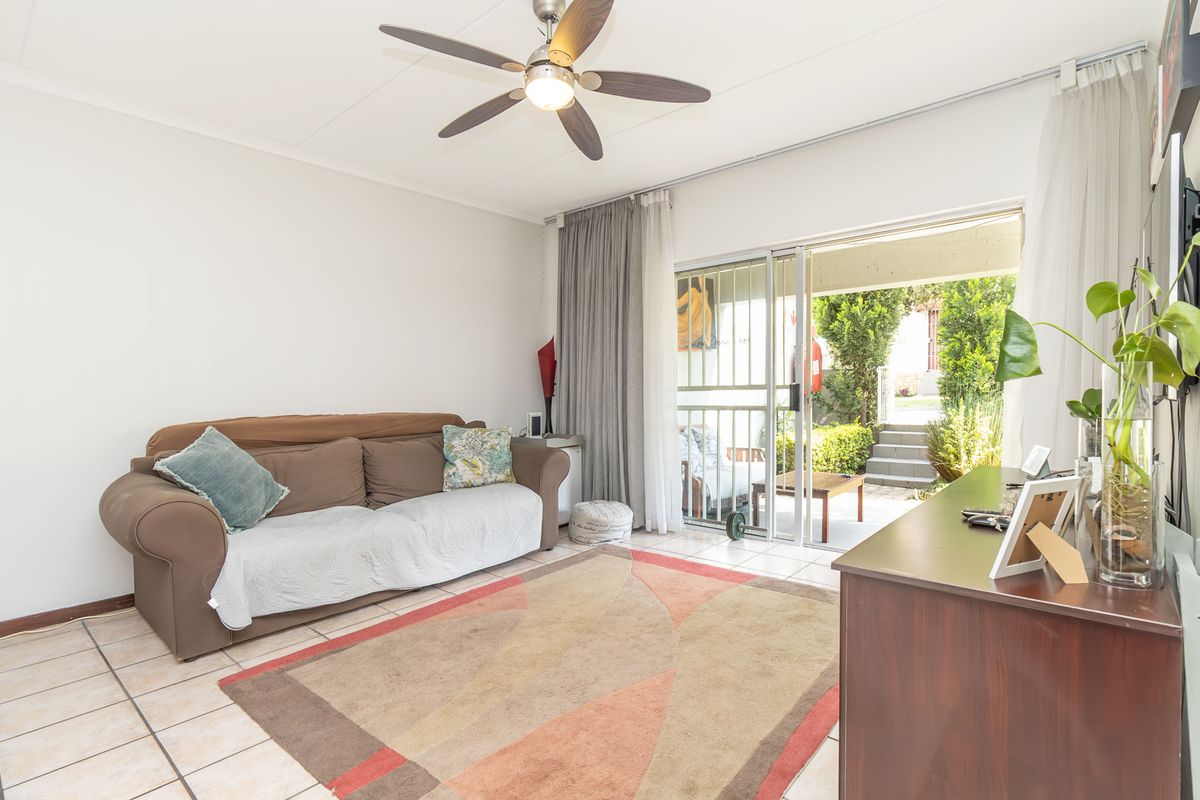 A bright living room featuring tiled flooring, a ceiling fan, and sliding glass doors that provide direct access to an outdoor patio area.
